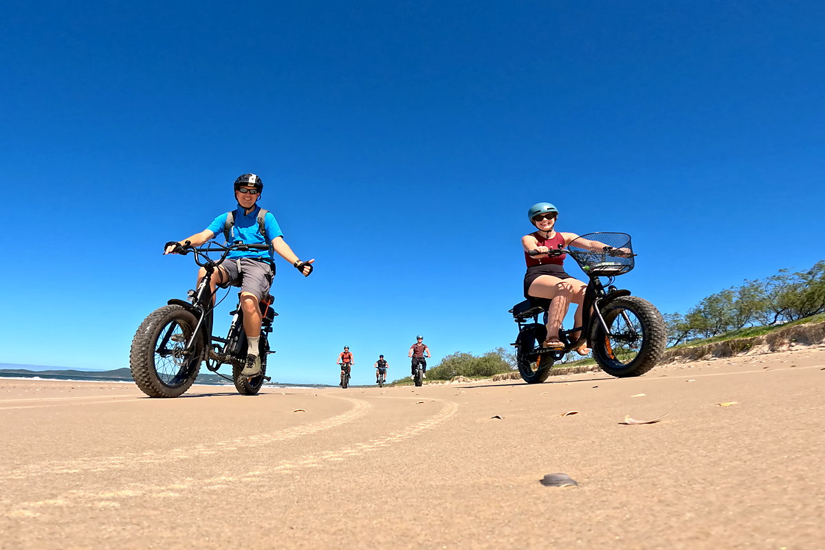 Two riders on fat bikes on the sand at Noosa North Shore