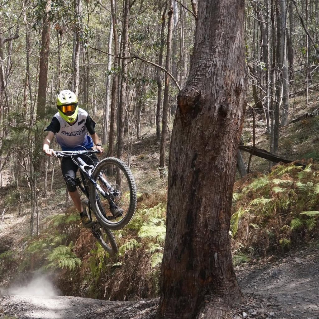 Advanced Development rider jumping past a tree on a hinterland trail