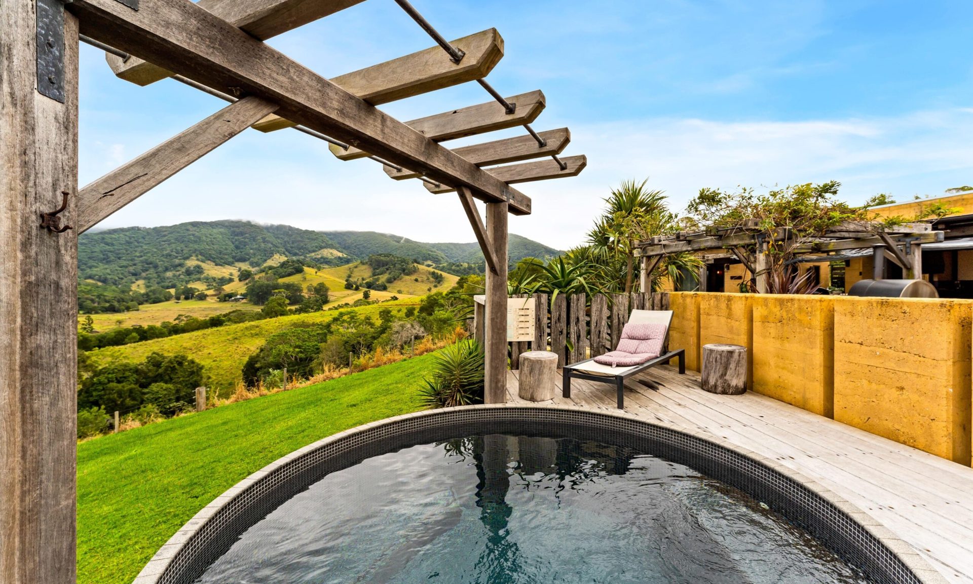 Wood-fired hot tub on a deck overlooking green hills at Mayan Farm Villas, Kin Kin