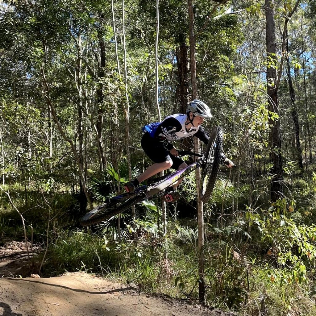Rider airborne off a jump on a Wooroi forest trail