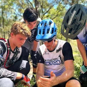 Bike On coach showing young riders a skill on his phone during an after school session