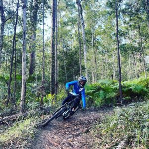 Rider in a Bike On jersey carving a berm through forest singletrack