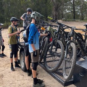 Young riders loading mountain bikes onto the Bike On trailer on a road trip