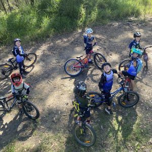 Young riders smiling up at the camera on a dirt trail