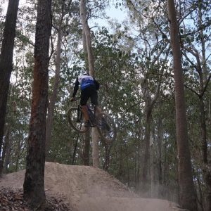 Rider in a Bike On jersey jumping a tabletop in tall forest